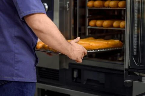 Unrecognizable professional baker at bakery with bread baguette 스톡 사진