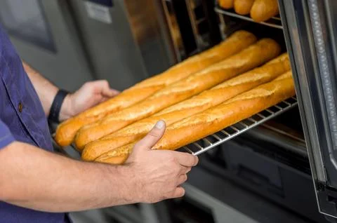 Unrecognizable professional baker at bakery with bread baguette Foto stock