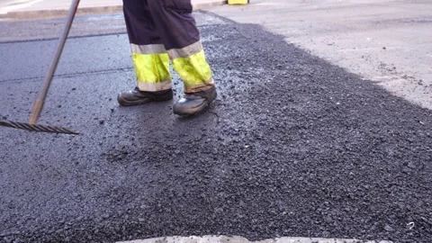 Unrecognizable road worker treating warm mix asphalt in road paving Stock Footage 253231258