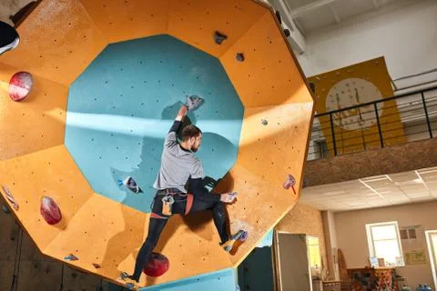 Unrecognizable rock-climber without forearm climbing up high at round wall Stock Photos