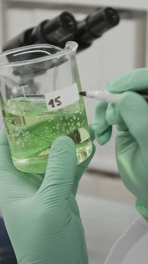 Unrecognizable Scientist Labeling Flask Containing Green Fluid in Laboratory Stock Footage 321896455