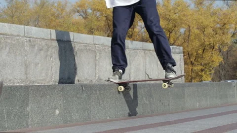Unrecognizable skater doing trick nose slide to fakie on the street ledge Stock Footage 96792369