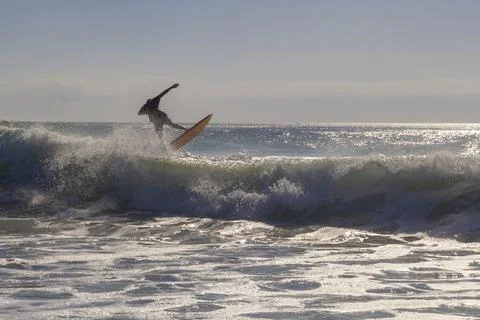 Unrecognizable surfer jumping over a wave, silhouetted against the sky at gol Foto stock