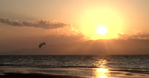 Unrecognizable surfer practicing kitesurfing on the beach during a sunset in Stock Footage 151379573