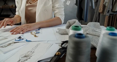 An unrecognizable tailor is working at her office, drawing sketches from paper Video stock 127147351