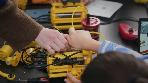 Unrecognizable Teacher Helping Little Student to Construct Robot Stock Footage 304145532