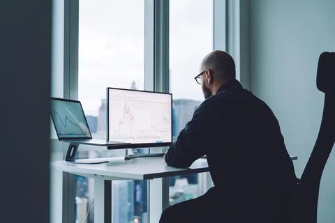 Unrecognizable trader studying graphs on computer monitors at work Stock Photos