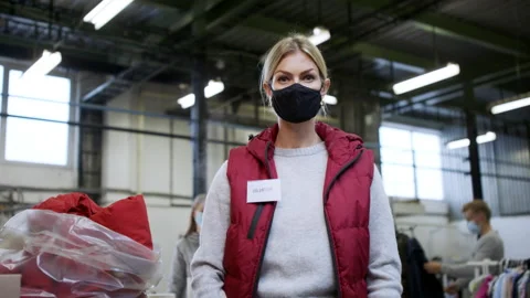 Unrecognizable volunteers sorting out donated clothes in community charity Stock Footage 150066157
