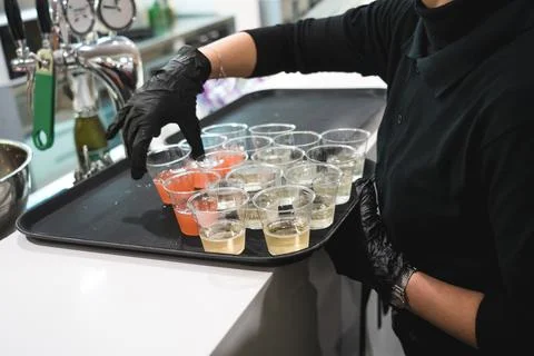 Unrecognizable waitress with black gloves preparing alcoholic drinks on a tray Stock Photos