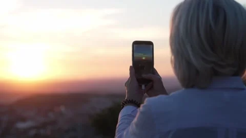 Unrecognizable woman capturing sunset with smartphone Stock Footage 341824013