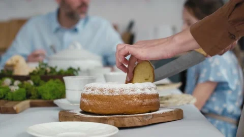 Unrecognizable woman cutting easter cake and passes a piece to the family in the Stock Footage 170834034