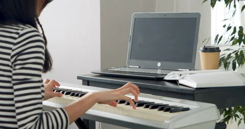 Unrecognizable woman playing electronic piano learning online using laptop Stock Footage 149083853