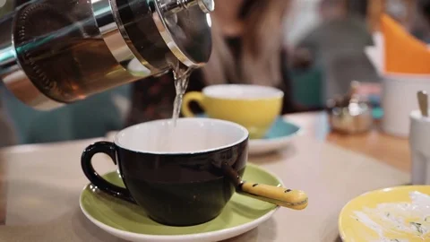An unrecognizable woman pours tea using a Frenchpress in a cup at a restaurant Video stock 82409370