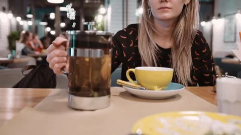 An unrecognizable woman pours tea using a French press in a cup at a restaurant Stock Footage 82440071