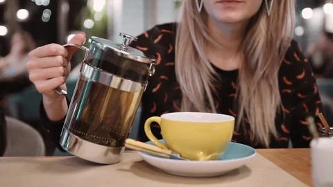 An unrecognizable woman pours tea using a Frenc hpress in a cup at a restaurant Stock Footage 82440512