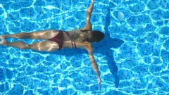 Beautiful slim girl in a white bikini swimming under clear water