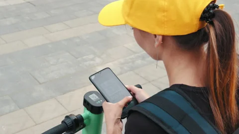 Unrecognizable Woman scan QR code by smart phone to unlock and rent electric Stock Footage 171987056