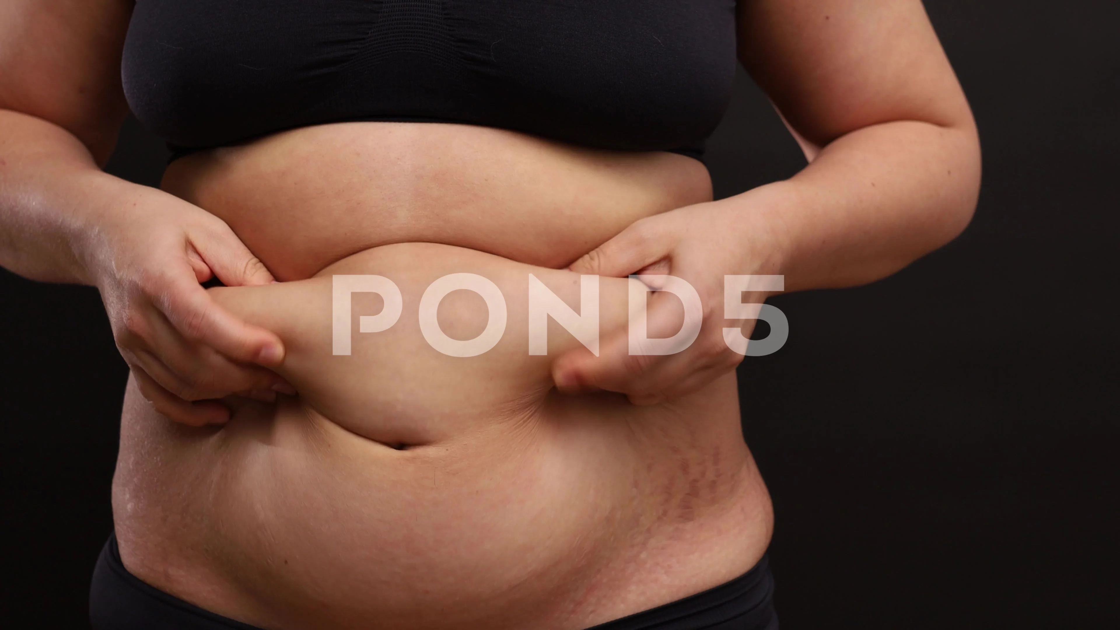 Unrecognizable black woman in underwear showing excessive fat on belly  Stock Photo by Prostock-studio