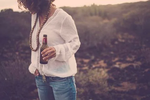 Unrecognizable woman standing outdoor with beer bottle -desert and light in b Stock Photos