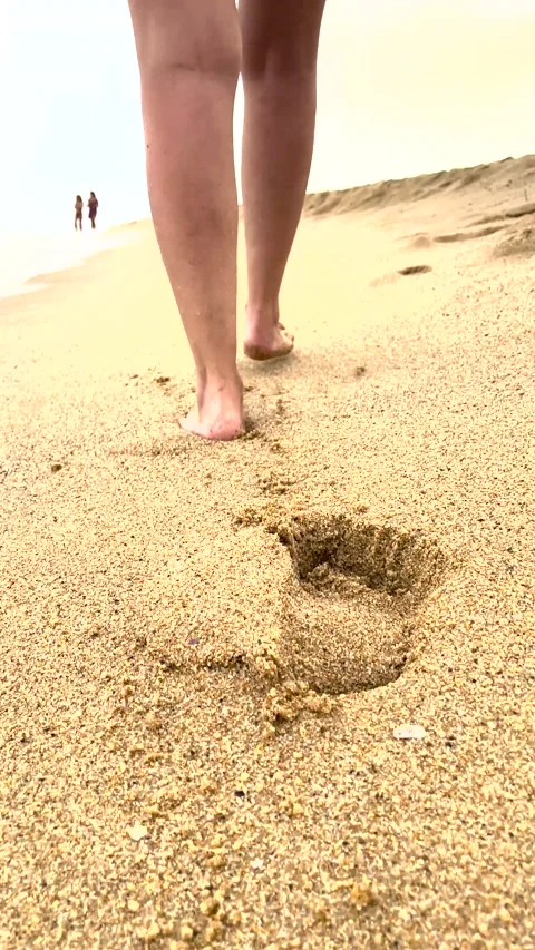 Unrecognizable woman walking on the beach while the waves are crushing on her Stock Footage 231568153
