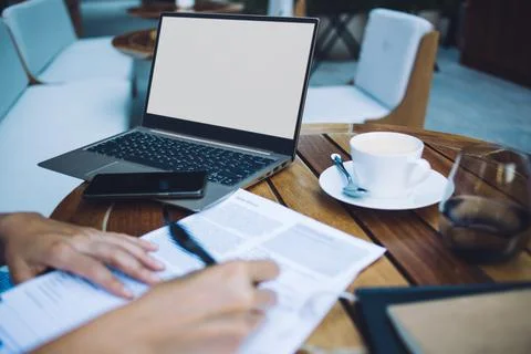 Unrecognizable woman writing in notepad while working on laptop Stock Photos