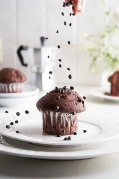 Unrecognizable woman's hand throwing chocolate chips on a homemade cupcake Stock Photos
