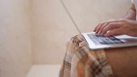Unrecognizable workaholic man in pajama bottoms typing on a laptop computer.. Stock Footage 342761176