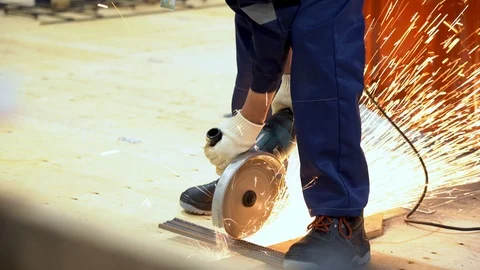 Unrecognizable worker cuts metal rods into bars on construction site, sparks fly Stock Footage 126356950