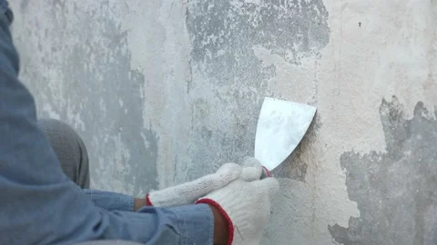 Unrecognizable worker shaving or peeling off old paint from wall Stock Footage 169079928