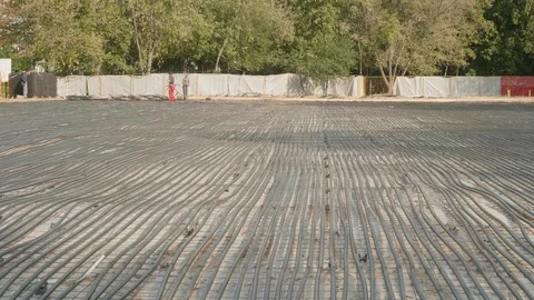Unrecognizable workers put black plastic tubes on dry concrete. Building of new Stock Footage 120636890
