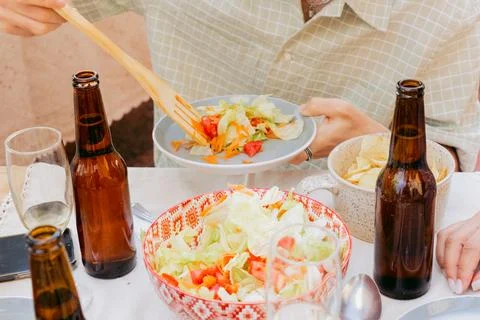 Unrecognizable young man, at shared lunch, serves salad Stock Photos