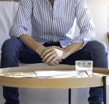 Unrecognizable young man sitting in the sofa with shirt on and held hands wit 库存照片