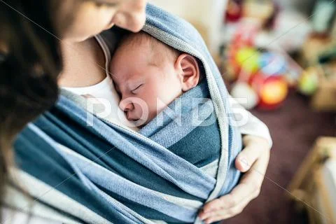 Unrecognizable young mother with her son in sling Stock Photos