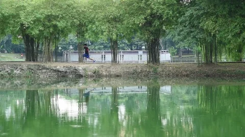 Unrecognized asian man exercise in park near pond Stock Footage 83305281