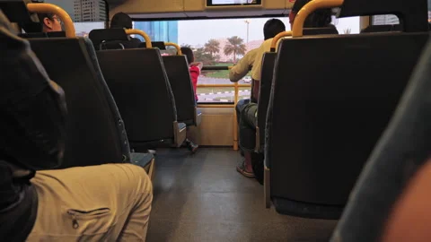 Unrecognized boy sits near a window in a double-decker modern bus. Palm trees Video stock 132968310