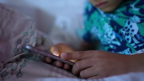 Unrecognized kid on bedroom playing with smart phone scrolling and browsing Stock-Footage 336249791
