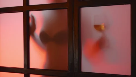 Unrecognized nude model shows glass of wine behind matt glass at sunset, slow mo Stock Footage 256664997