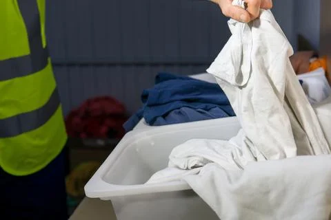 Unrecognized operator working at a textile recycling plant holds white garment Stock Photos