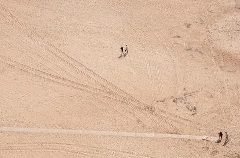 Unrecognized people walking on an empty sandy tropical beach. Nazare Portugal Stock-Fotos