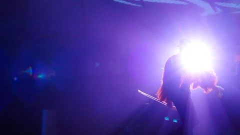 An unrecognized performer in dramatic lighting is captivating the audience with Stock Photos