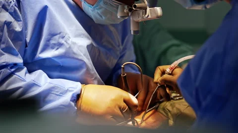 Unrecognized surgeons in brown latex gloves apply surgical tools. Doctors Video stock 331081668