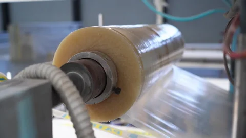 Unrolling coil with transparent plastic foil on packaging line Video stock 304390664