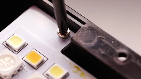 Unscrewing component on an LED lamp circuit board Stock Footage 336559715