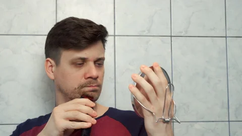 Unshaven man shaving cheeks, beard, moustache with electric safety razor. Stock-Footage 153700552