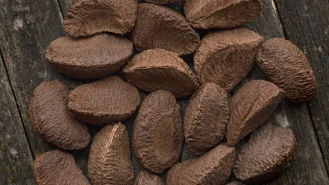 Unshelled Brazil nuts pile on a rustic wooden table. Stock Footage 342348647