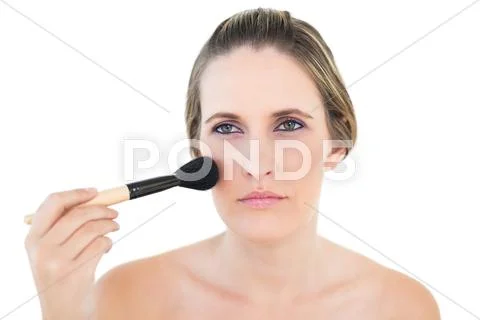 Unsmiling woman using blusher brush Stock Photos