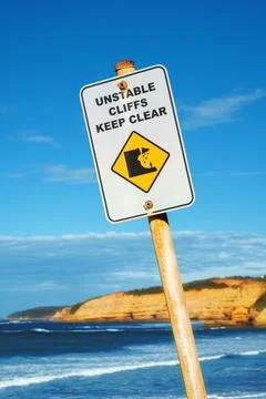 Unstable Cliffs Keep Clear sign with rocky coastline in distance Stock Photos