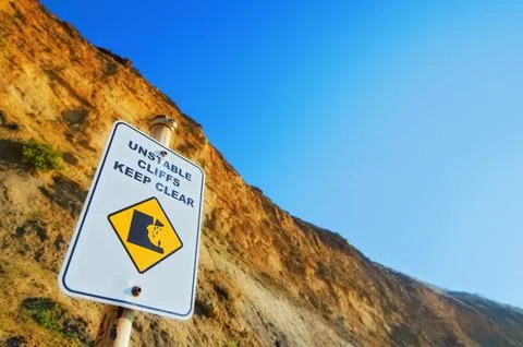 Unstable Cliffs Keep Clear sign in front of tall limestone cliffs Stock Photos