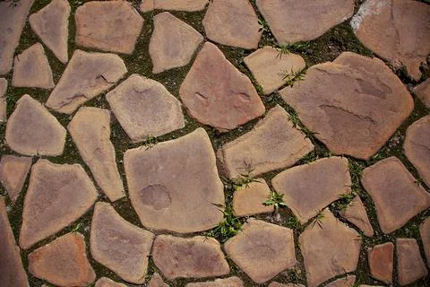 Unstructured tiled road consisting of peaces of flat stones put into ground with Stock Photos