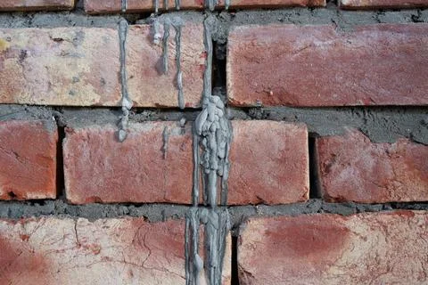 Untidy brickwork with gaps unfilled with cement mortar. Abstract background. Stock Photos